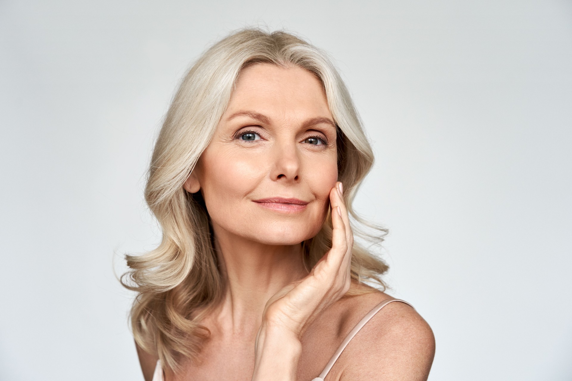 Beautiful gorgeous 50s mid aged mature woman looking at camera isolated on white. Mature old lady close up portrait. Healthy face skin care beauty, middle age skincare cosmetics, cosmetology concept